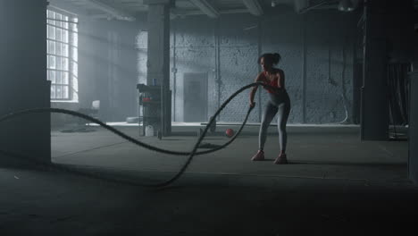 woman doing workout with battle ropes. girl performing crossfit exercise