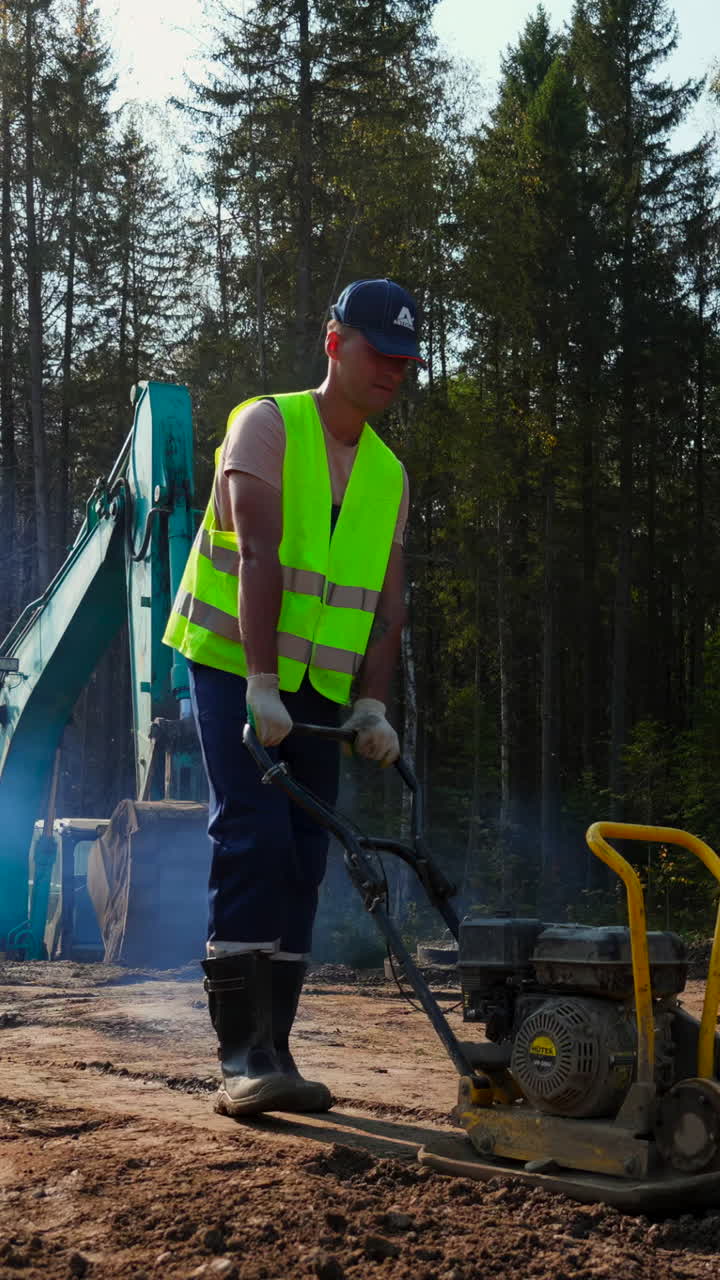 Construction worker operating a plate compactor on a construction site