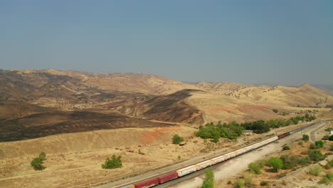 tren rodando por las vías bajo una ladera quemada por incendios forestales estacionales cerca de caliente, california