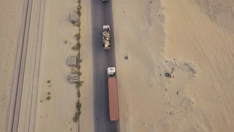 fly over a long line of trucks in the desert over a cracked road