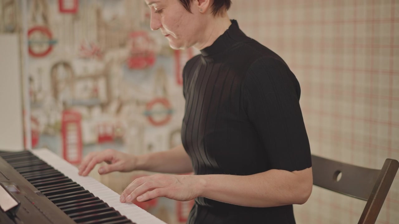 Musicista donna che suona una tastiera elettronica, in un ambiente accogliente di un'aula, concentrata sullo spartito e sulle mani che si muovono sui tasti, dimostrando tecnica e postura, insegnando attraverso tempo e dinamiche, caldo