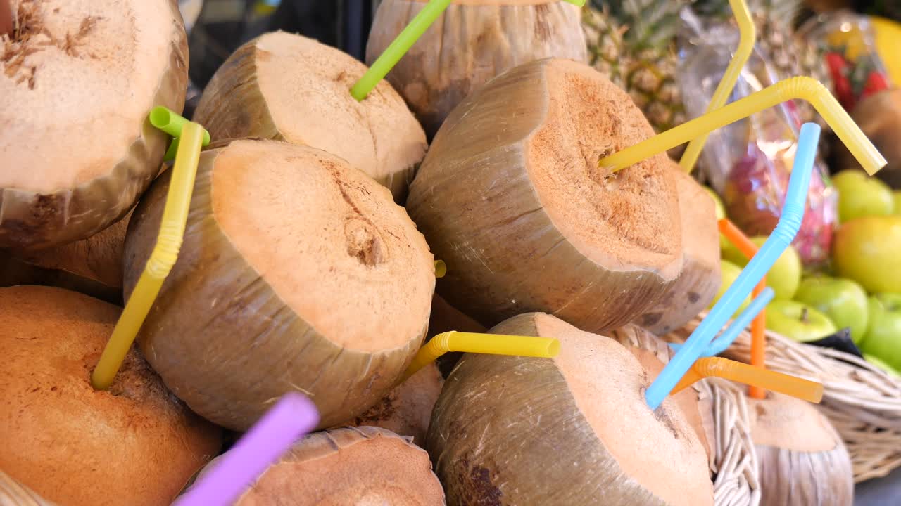 Giovani noci di cocco rinfrescanti con cannucce colorate in un mercato