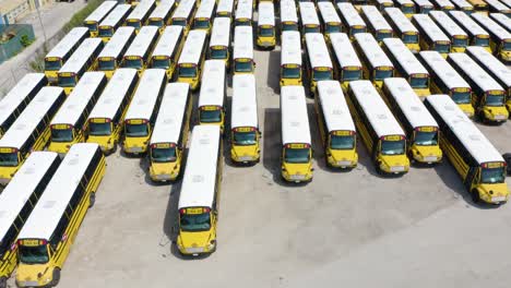 drone view of school bus parking lot full of buses parked for summer