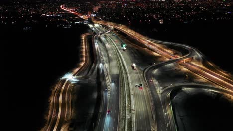 Aerial-flyover-traffic-jam-interchange-road-at-night,-drone-shot-top-down-view-roadway-intersection-in-modern-city-in-evening