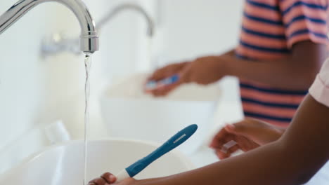 Brother-And-Sister-Sitting-In-Bathroom-At-Home-Brushing-Teeth-Together