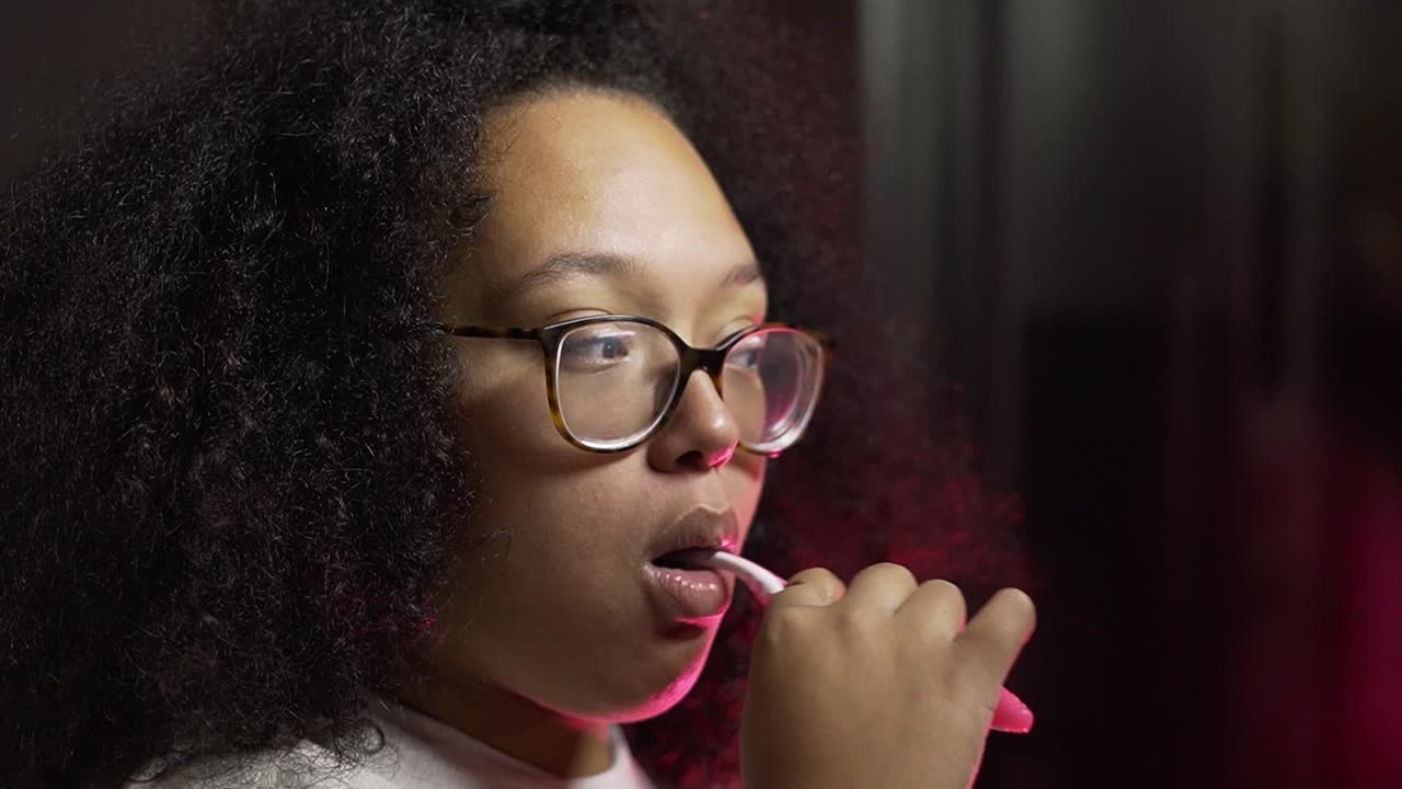 Black lady brushing her teeth in her bathroom