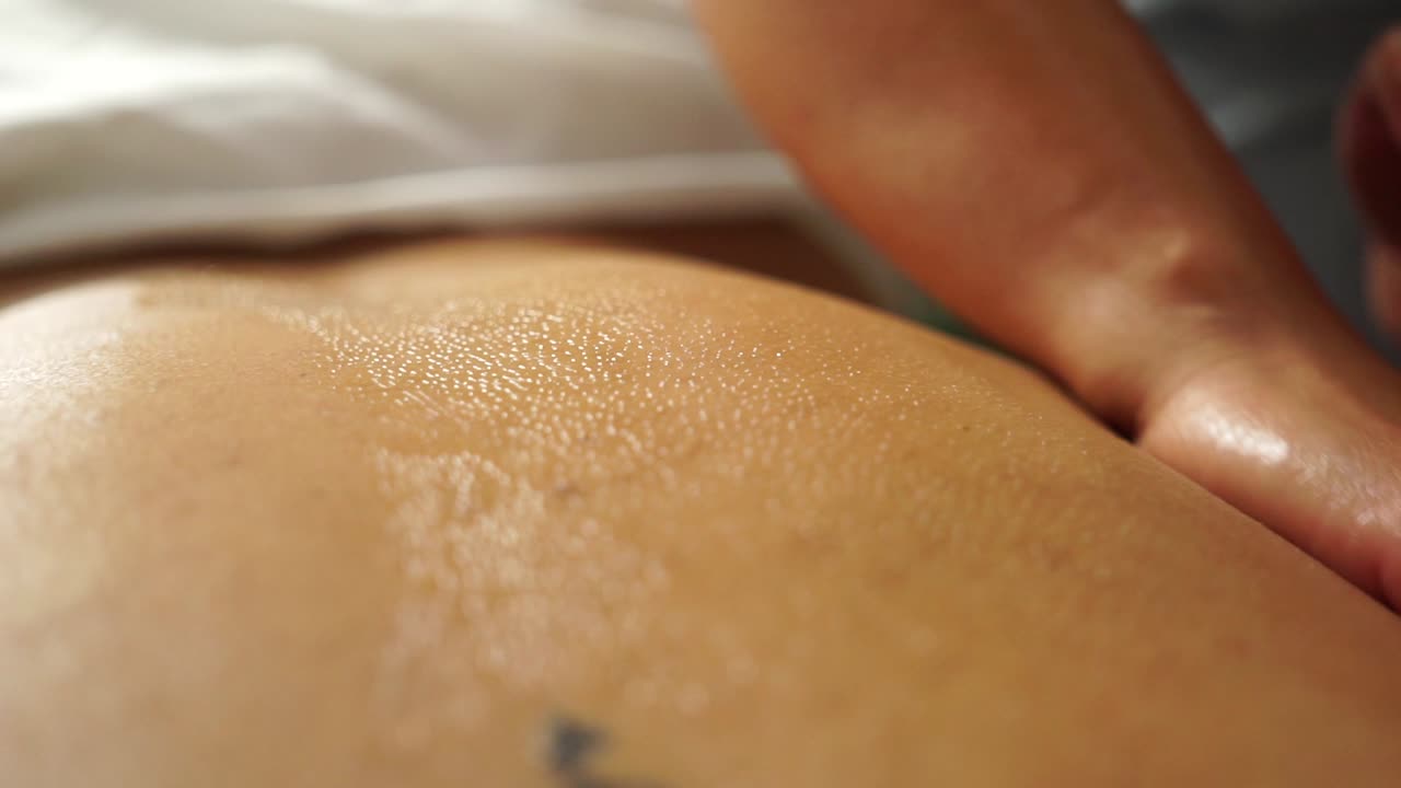 Primo piano di mani che praticano massaggio terapeutico, donando benessere a una bella donna in relax in una spa