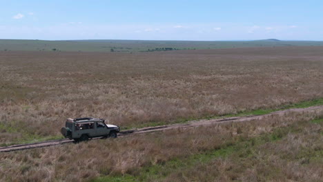 circling drone shot of off-road vehicle drives through grasslands in serengeti