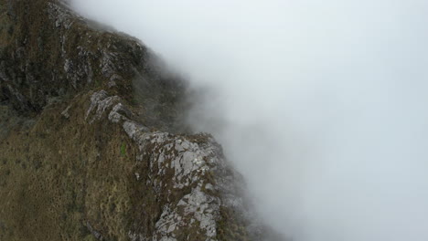 aerial view of steep hills and dense clouds under rucu pichincha volcano ecuador - drone shot