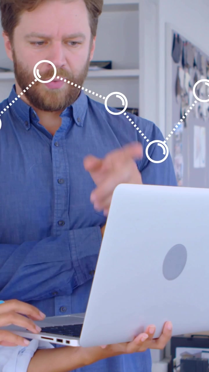 Video verticale: Uomo che osserva e consulta mentre una donna digita sul laptop, con un grafico che anima dati aziendali.