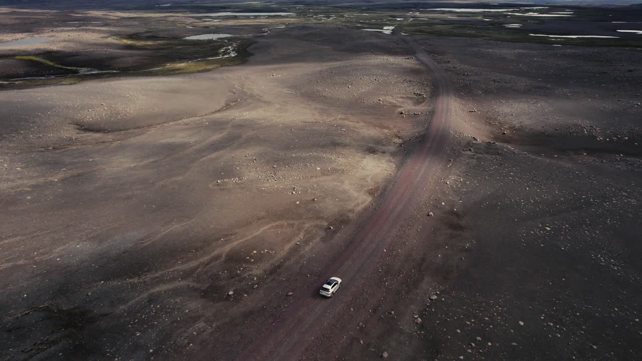 drone siguiendo un auto plateado filmado desde el lado derecho conduciendo fuera de la carretera en el campo lunar de islandia en 4k