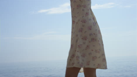 barefoot woman splashing ocean water by legs close up. girl walking on sea waves