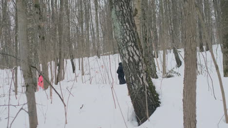 a man and a woman run in the park in winter and jump over a fallen tree. step over the obstacle