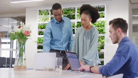 Gente-De-Negocios-Feliz-Y-Diversa-Discutiendo-El-Trabajo-Y-Usando-Una-Computadora-Portátil-En-La-Oficina,-Cámara-Lenta