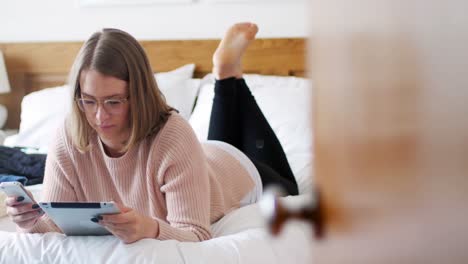 woman using digital tablet and mobile phone in bedroom