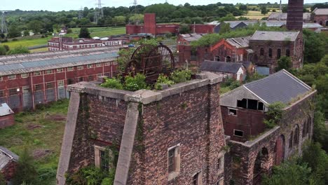 Abandoned-old-overgrown-coal-mine-industrial-rusting-pit-wheel-aerial-close-right-orbit-view