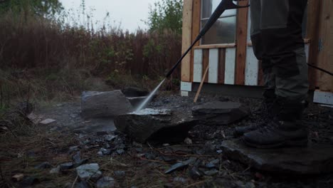 un hombre está usando una manguera de presión para limpiar las rocas destinadas a construir un invernadero en indre fosen, noruega - toma estática