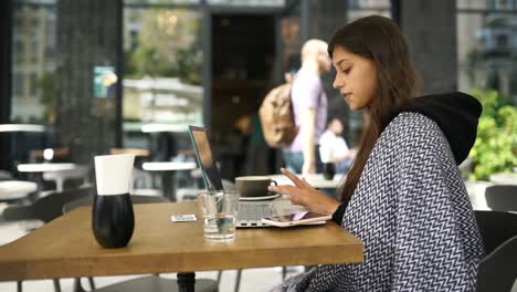 mujer trabajando en una computadora portátil en un café