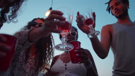 diverse friends dancing and drinking at lake party