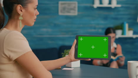 Back-view-of-woman-holding-tablet-computer-with-mock-up-green-screen