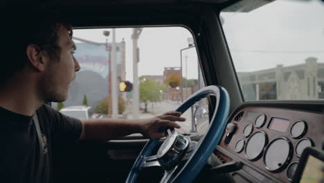 young truck driver shifting gears driving through city in cockpit view in slow motion