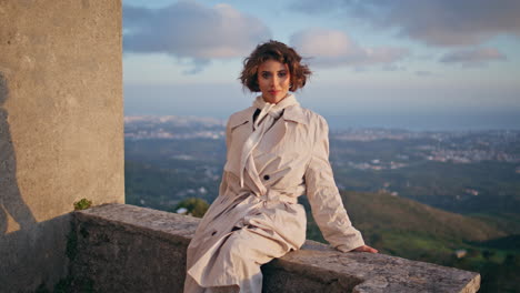 model posing ancient architecture at evening overlooking urban expanse.