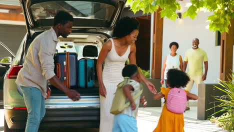 Grandparents-Greeting-Grandchildren-As-Family-Unpack-Car-On-Family-Holiday