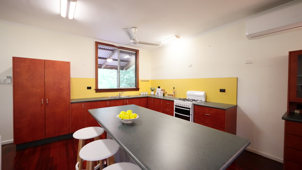 Colourful House With Wooden Floorboards And Cabinets, Lounge Dining Kitchen With Patterned throw pillow on couch and Large Plant on Table