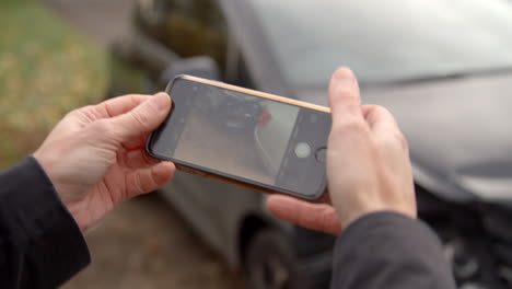 man taking photo of car accident on mobile phone