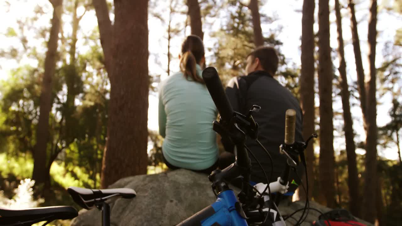 pareja de ciclismo de montaña tomando un descanso en el bosque