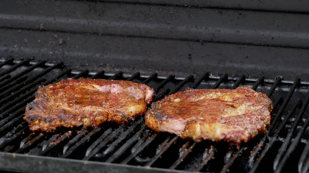 dos jugosos filetes de costilla sentados a la parrilla y cocinando