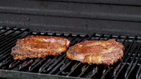 two juicy rib-eye steaks sitting on the grill and cooking