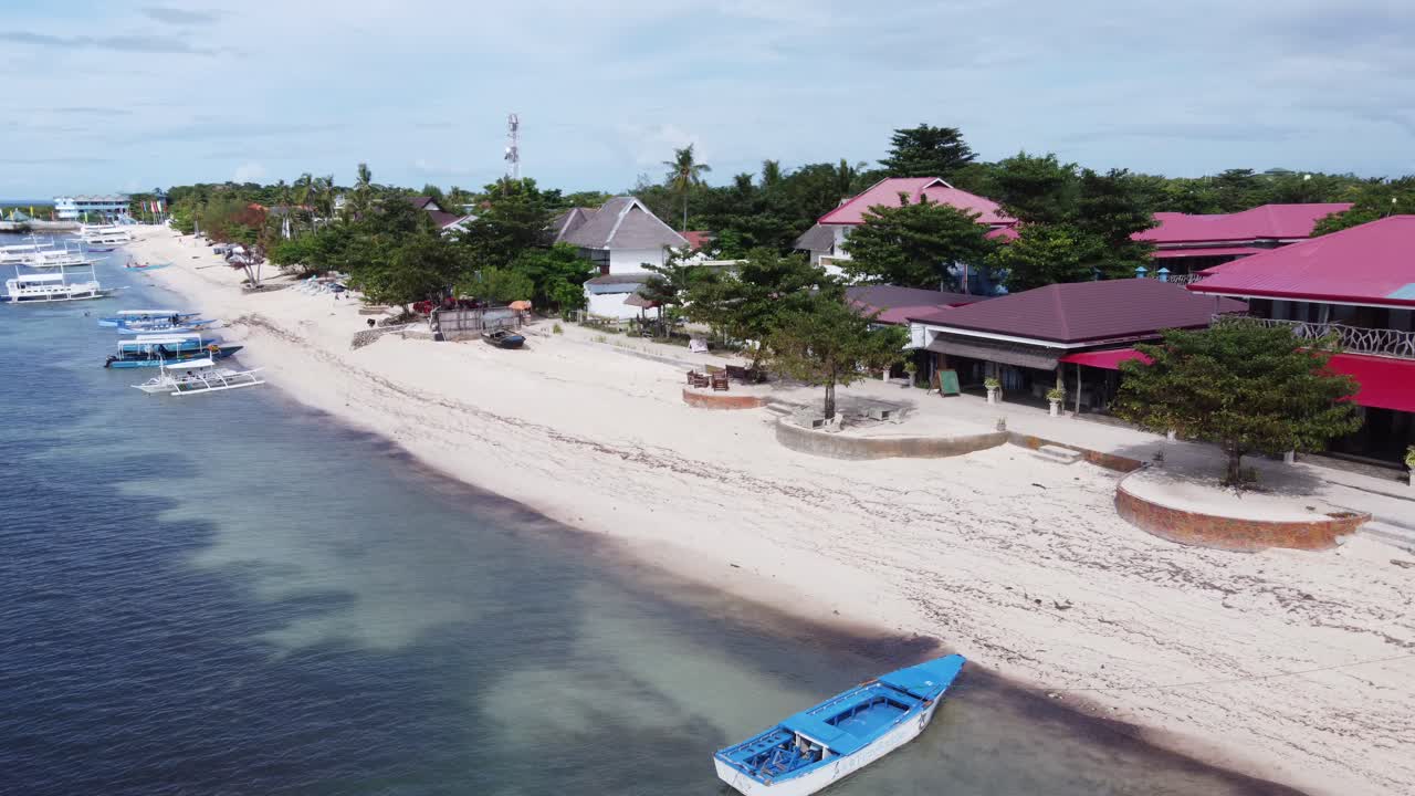 Bounty Beachfront on Malapascua Island with outrigger dive boats and colorful jukung canoes on white sand beach