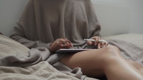 mujer trabajando en la tableta en la cama