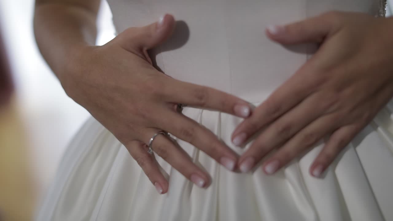 Bride in wedding dress. Hand touches dress. Pretty and well-groomed woman