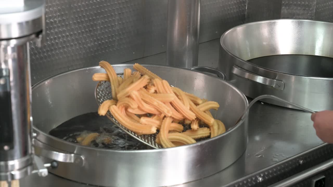 Inside a traditional Spanish churrería, a chef prepares a batch of fresh churros. The scene showcases the authentic craft of frying this beloved pastry, a staple of Spanish cuisine
