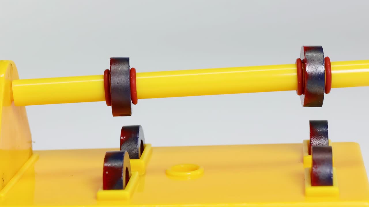 Close-up view of magnets rotating on a yellow stand, demonstrating magnetic interaction.