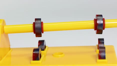 close-up view of magnets rotating on a yellow stand, demonstrating magnetic interaction.