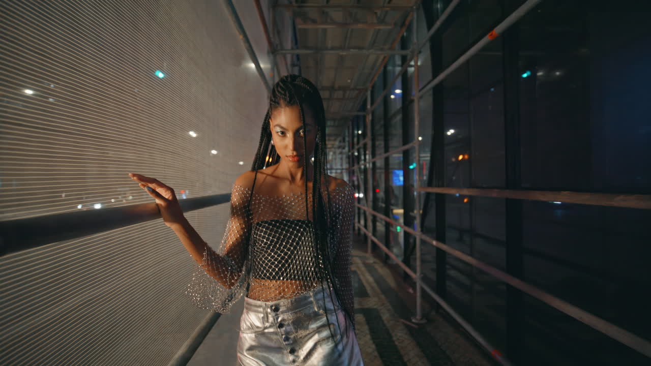 hermosa mujer caminando en el andamio nocturno en un primer plano de ropa de moda. modelo posando