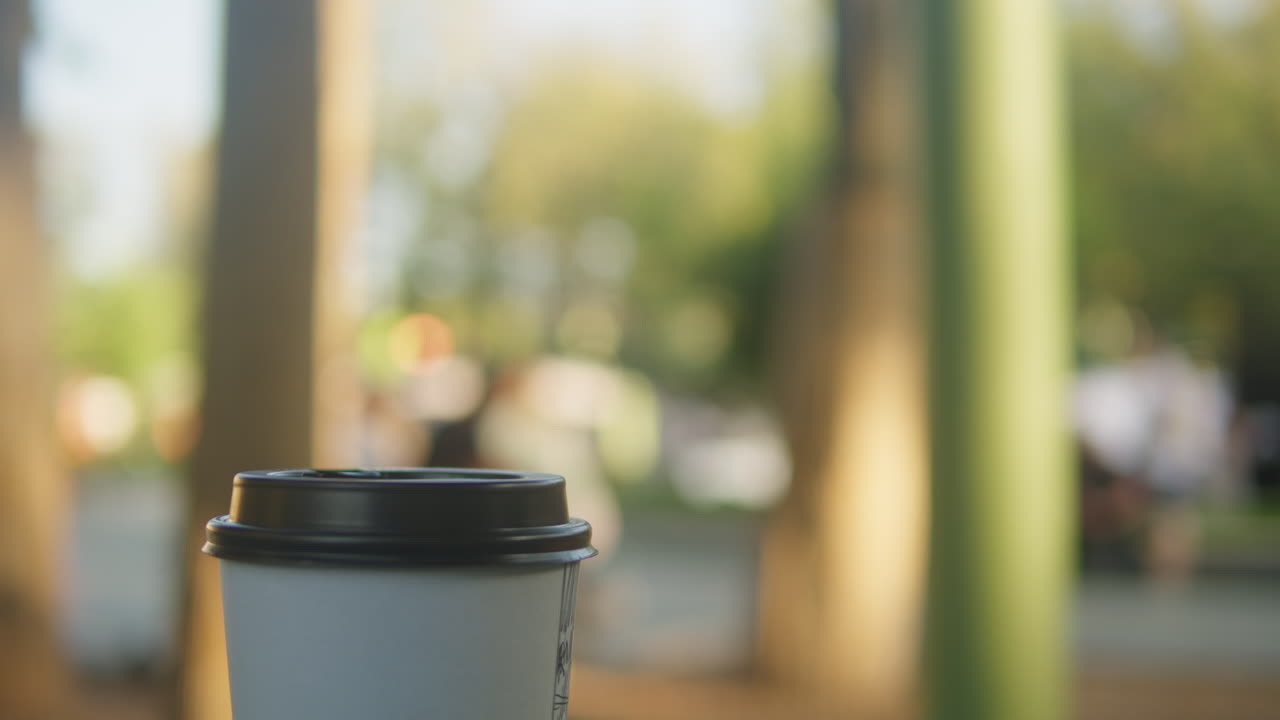 Cup of coffee to go nature backgroung close-up. Drink in carton cup on the table. Outdoors