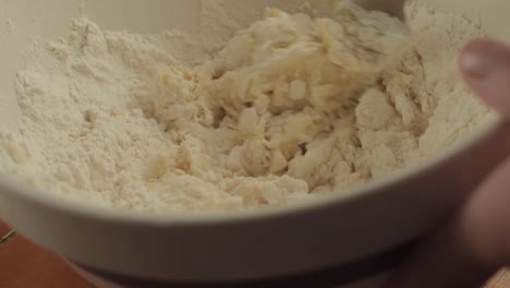 Hand-mixing-ingredients-with-flour-in-a-bowl-close-up-shot