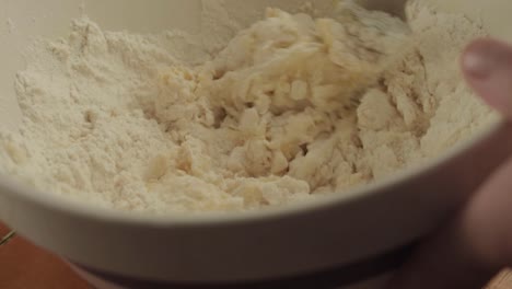 hand mixing ingredients with flour in a bowl close up shot