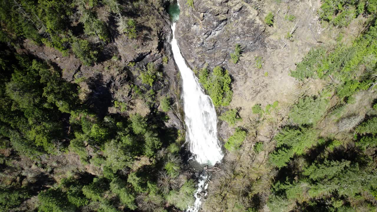 lentamente en órbita por encima de una cascada de agua, en lo profundo de un lugar remoto del bosque, avión no tripulado aéreo