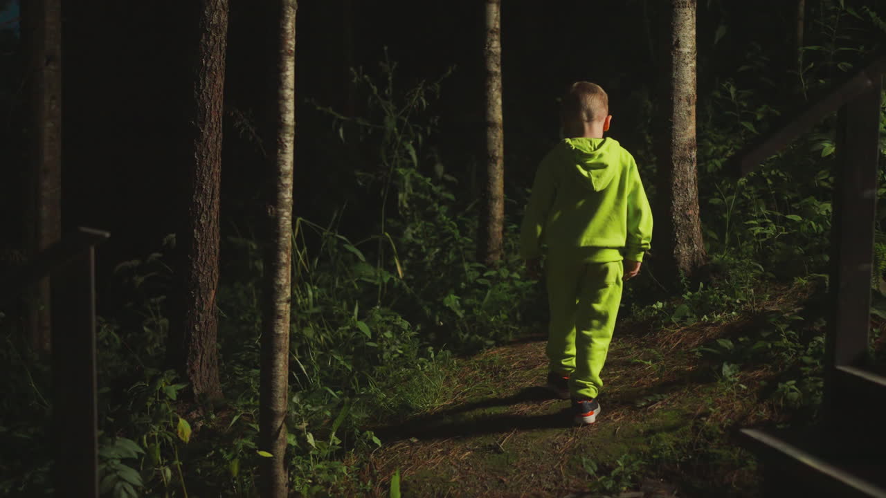밝은 운동복을 입은 호기심 많은 어린 소년은 혼자 숲으로 갔습니다. 아이는 모험을 찾기 위해 집의 계단에서 저녁 덤불로 들어갑니다. 자연 환경.