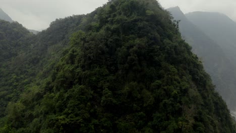 Aerial-rising-to-tropical-woodland-mountain-greenery-peaks-in-Taroko-Valley-cloudy-summit-mountain-wilderness