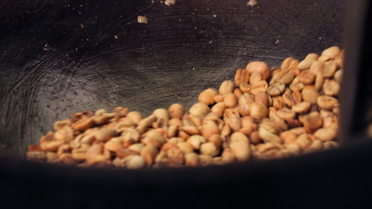 Slow motion shot of expensive and exclusive kopi luwak coffee beans being stirred and roasted in a wok with a wooden spoon in bali indonesia