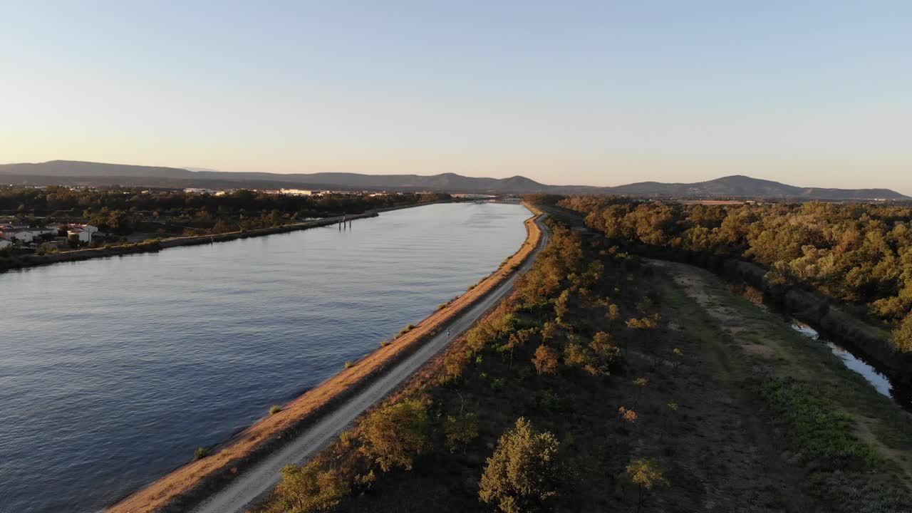 Aerial footage of the Rhine River in an industrial area with a bridge at dawn, showcasing the serene morning light reflecting on the water and structures.