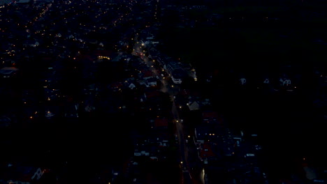 Antena-Alta-De-Un-Pequeño-Pueblo-Por-La-Noche-Con-Hogares-En-Llamas-Y-Farolas