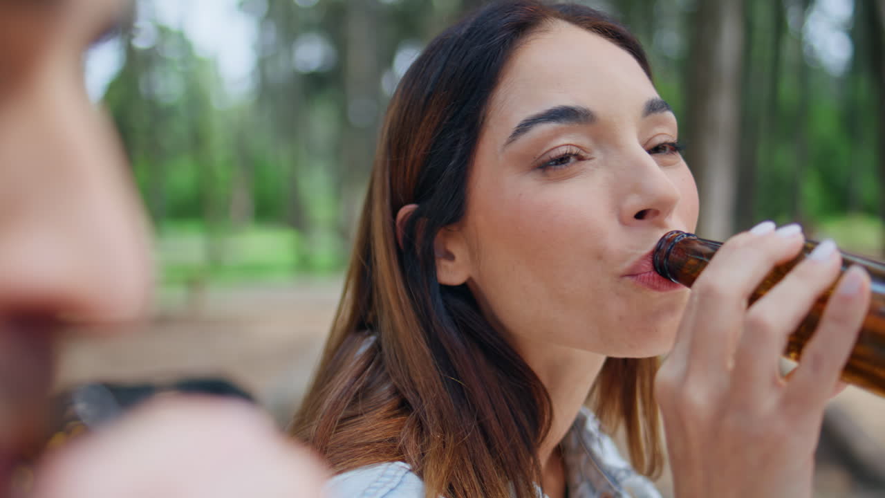 Excited brunette drinking beer on summer picnic closeup. Happy woman laughing