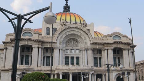 una toma completa con seguimiento del palacio de bellas artes en la ciudad de méxico, con farolas en primer plano, en un día despejado con cielo azul